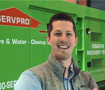 Man with brown hair standing in front servpro equipment