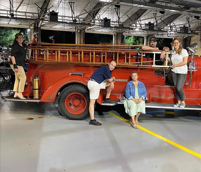 Group of people posing on top of an antique fire truck