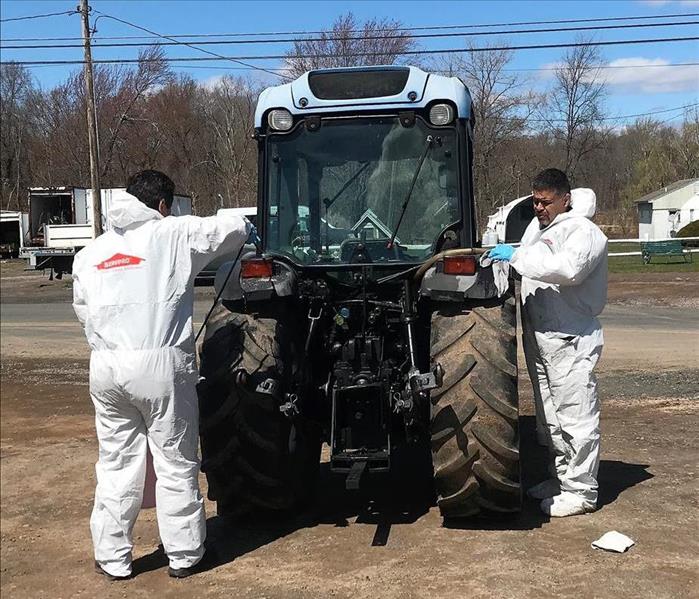 sERVPRO TECHS IN PROTECTIVE gear cleaning a tractor