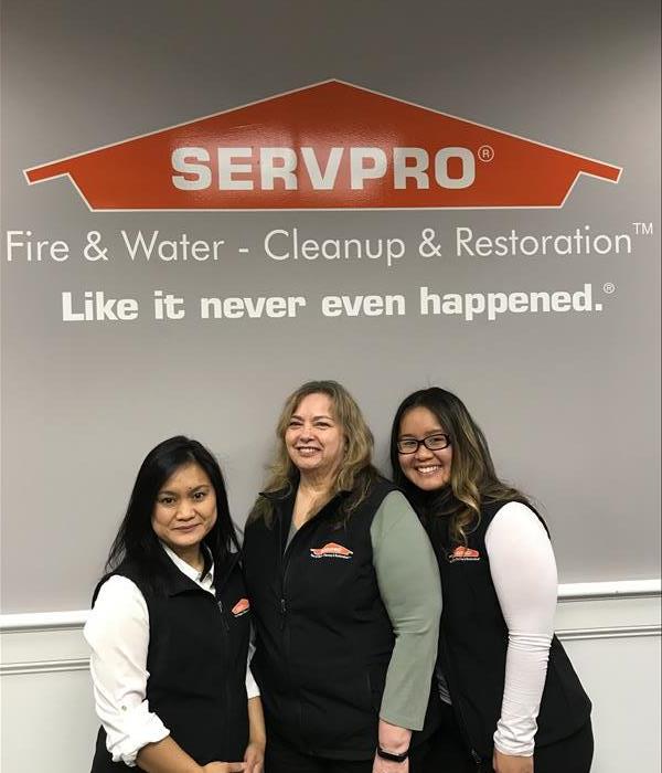 three ladies standing in front of a SERVPRO sign