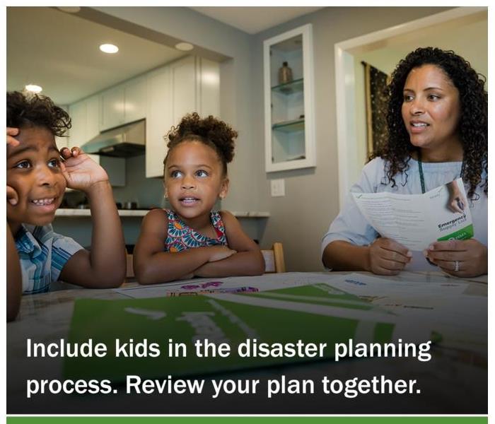 children sitting at the table with mother looking at emergency planning brochure