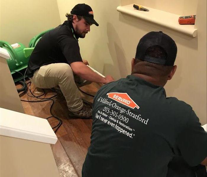 2 men in SERVPRO uniforms removing molding from a home