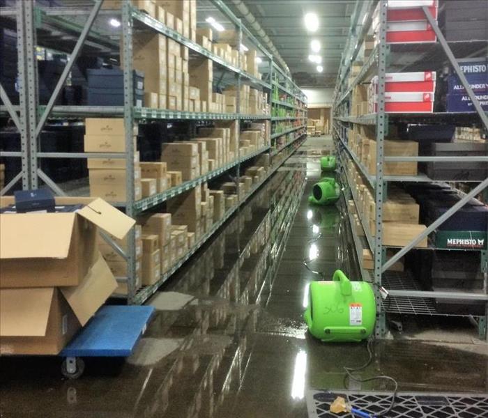 warehouse shelving loaded with boxes and water standing on floor